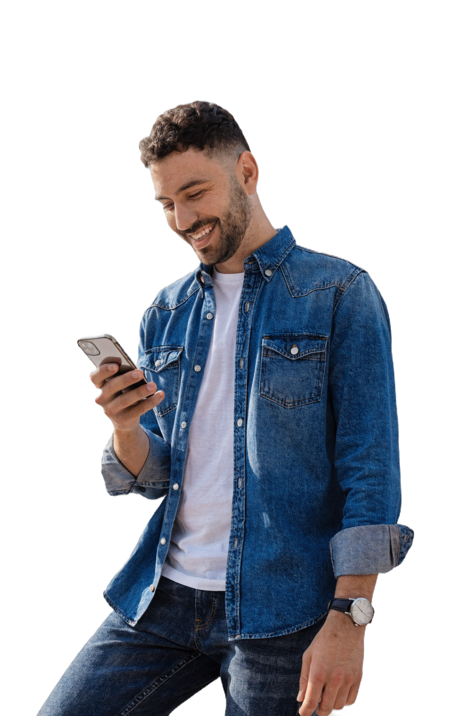 A young man in a denim shirt smiling at his phone, the moment of seeing a loan offer that fits.